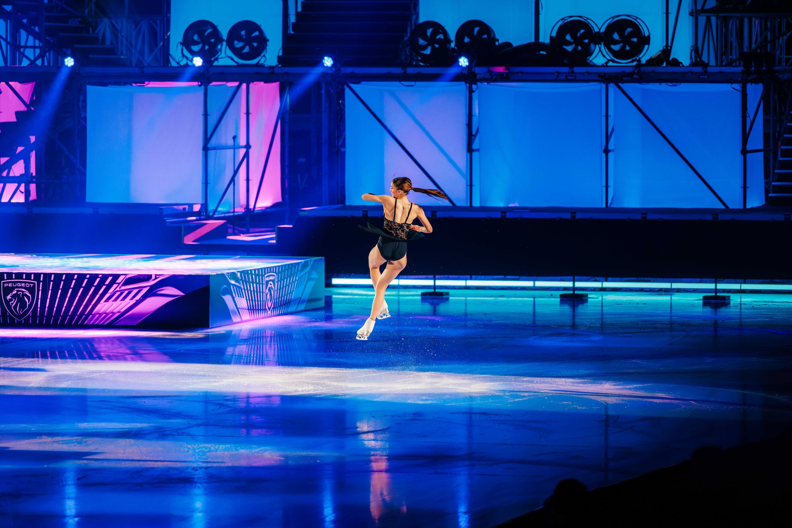 Eine Sololäuferin gleitet allein über die beleuchtete Eisfläche.