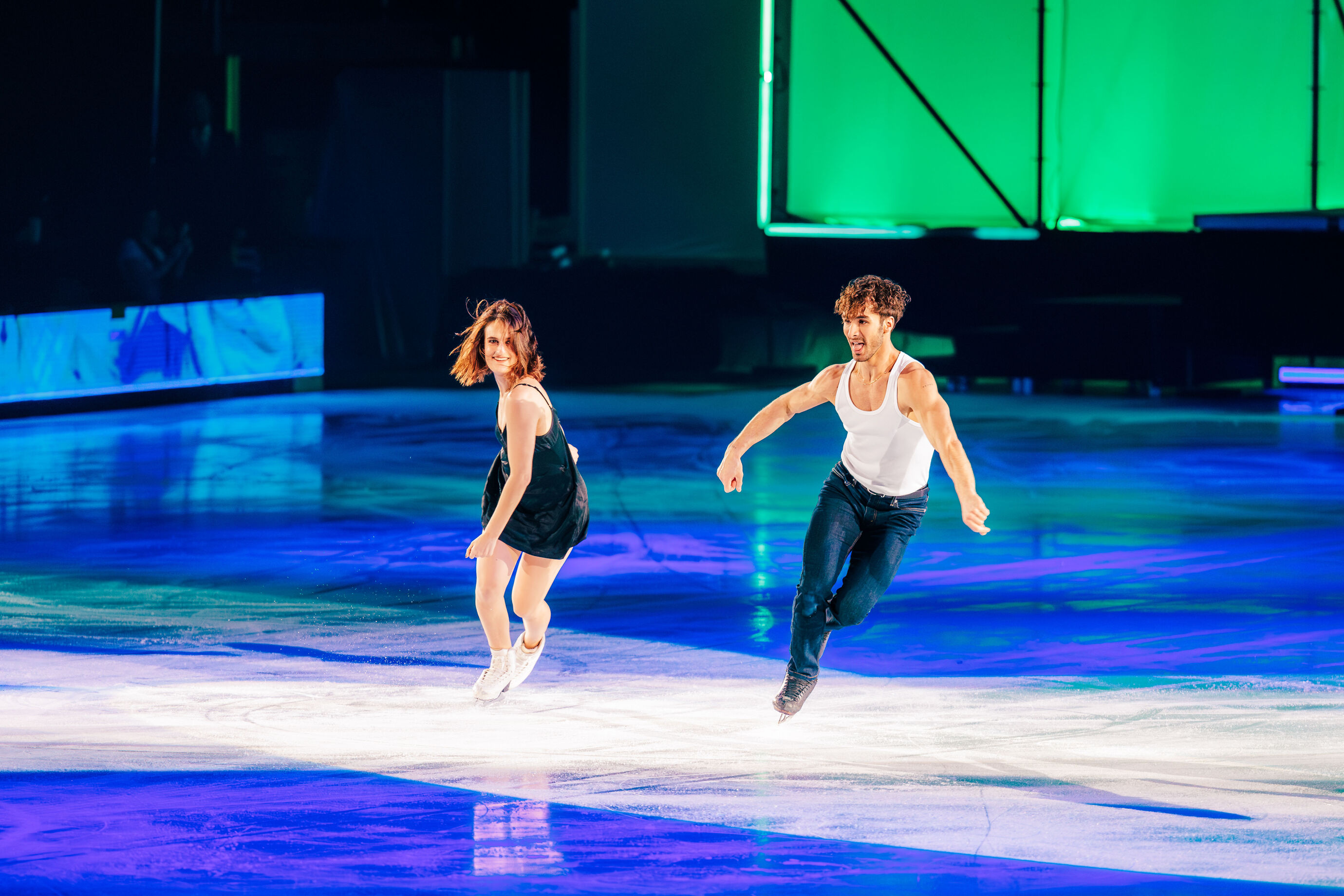 Zwei Eiskunstläufer gleiten synchron über die Eisfläche, voller Energie und Ausdruck.