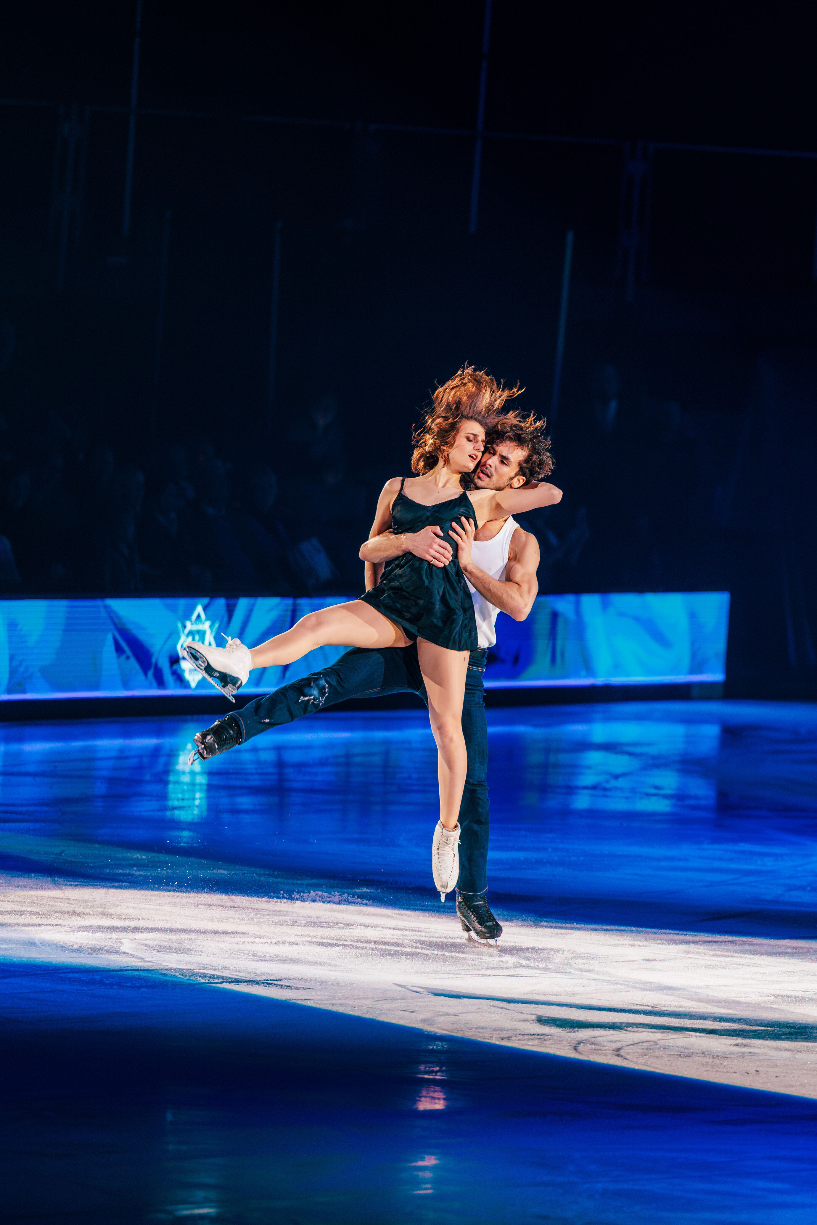 Eiskunstläufer hebt seine Partnerin hoch über die Eisfläche