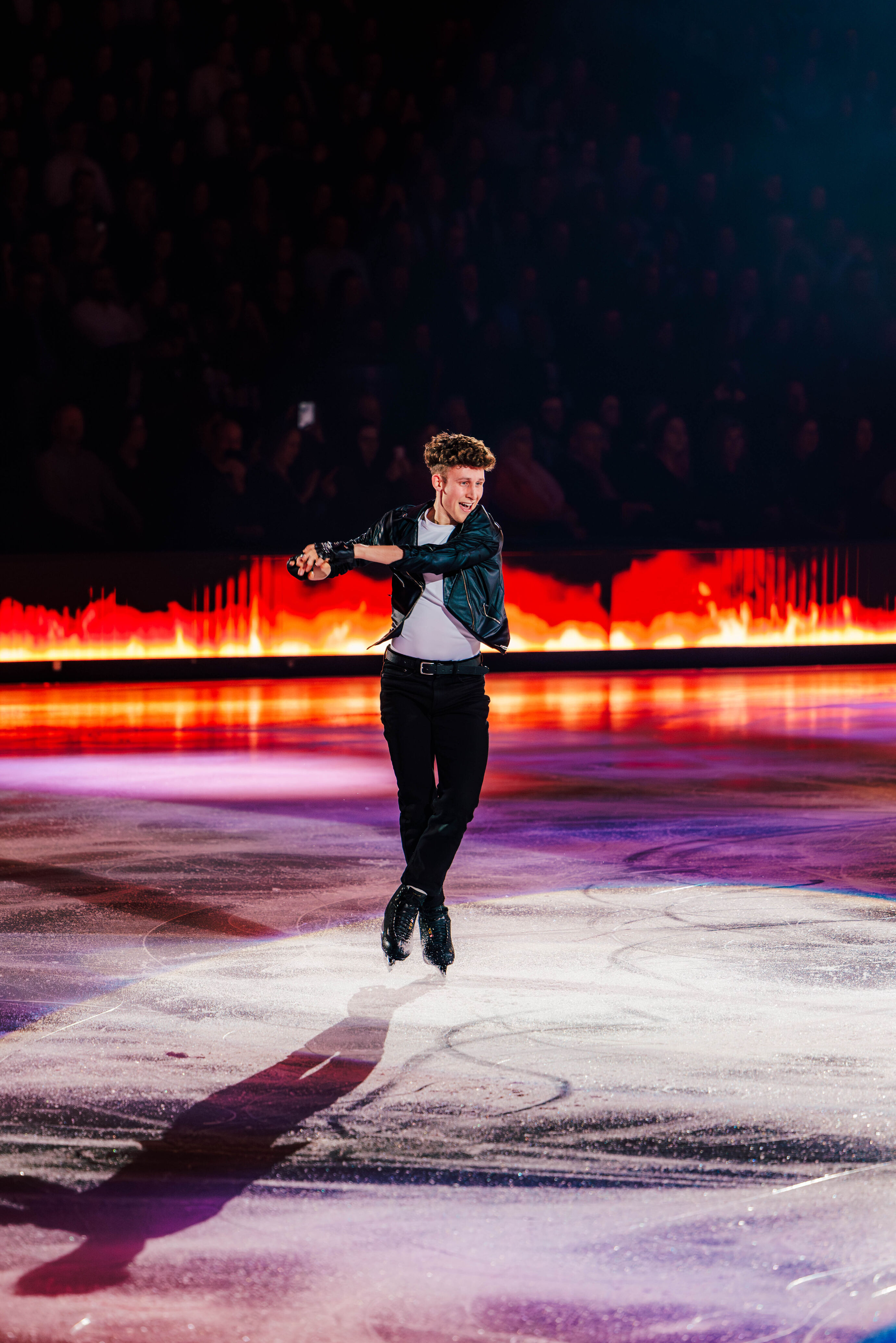 Ein Eiskunstläufer springt mit ausdrucksstarkem Gesichtsausdruck hoch in die Luft.