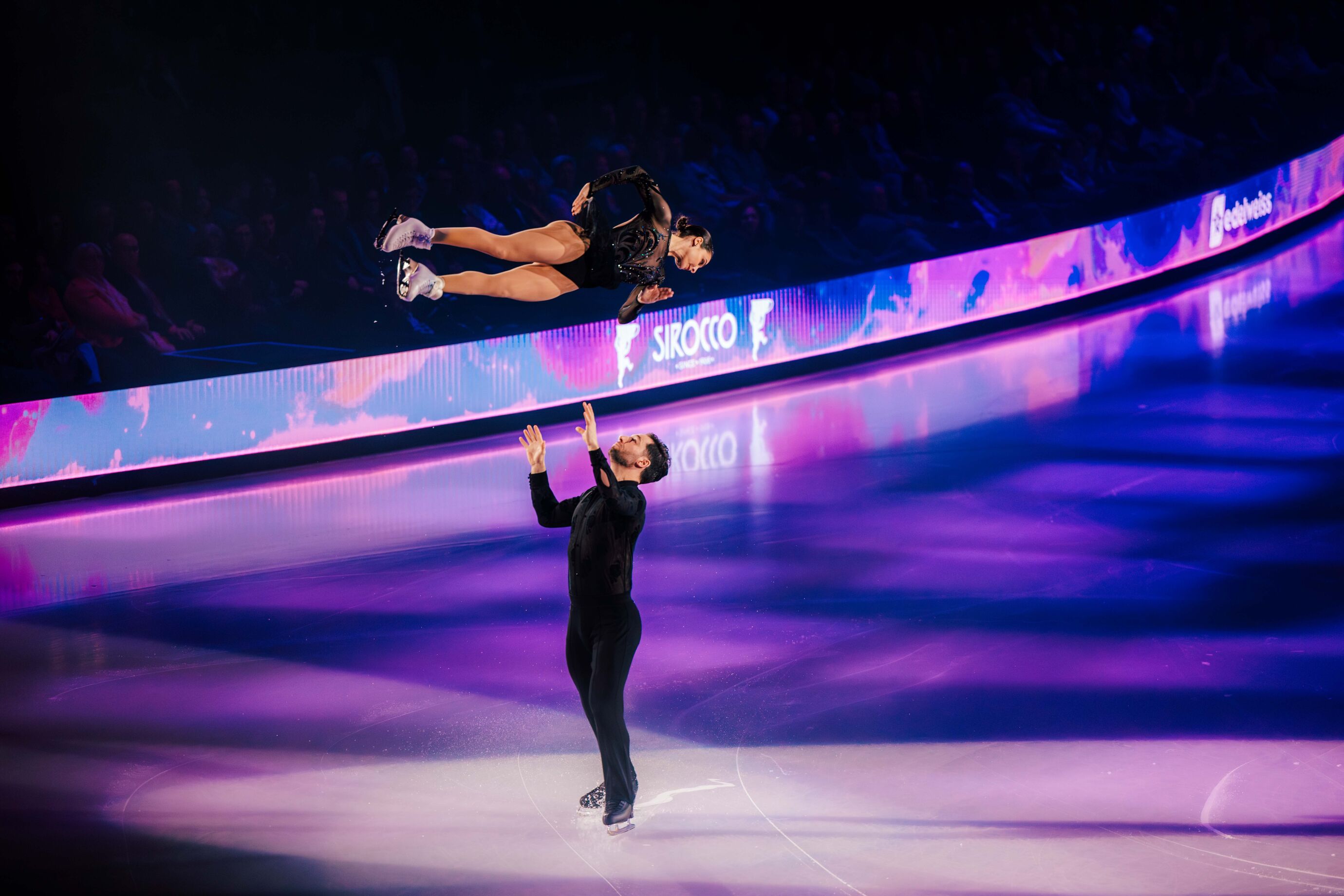Partner hebt Eiskunstläuferin in luftige Höhe während der Show
