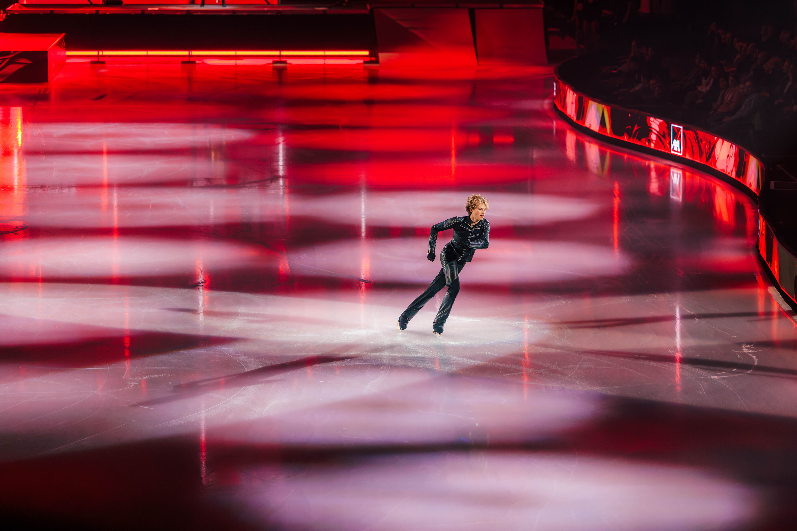 Eiskunstläufer in Solo-Performance im roten Scheinwerferlicht
