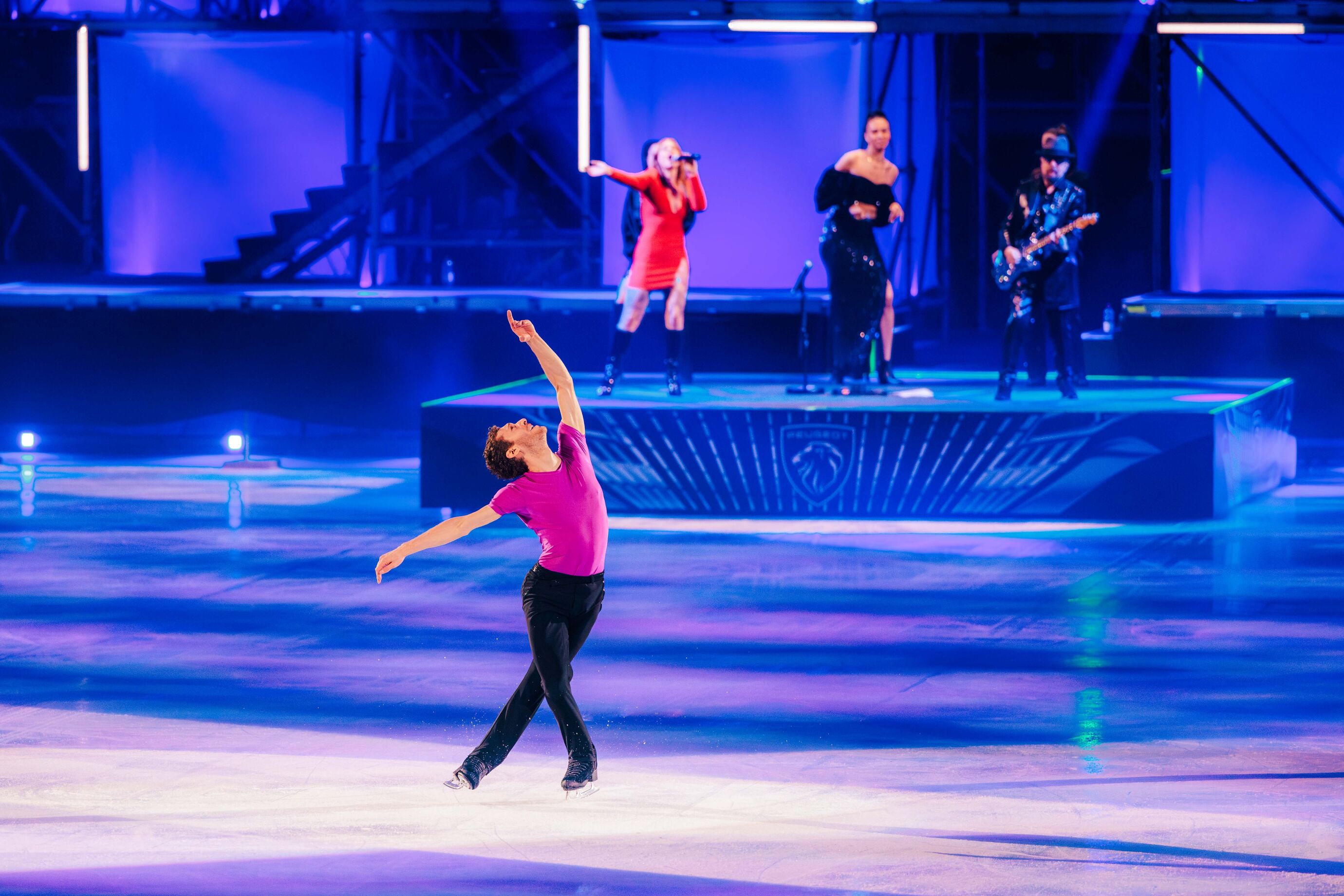Ein Sololäufer im pinken Shirt performt, während die Band live im Hintergrund spielt.