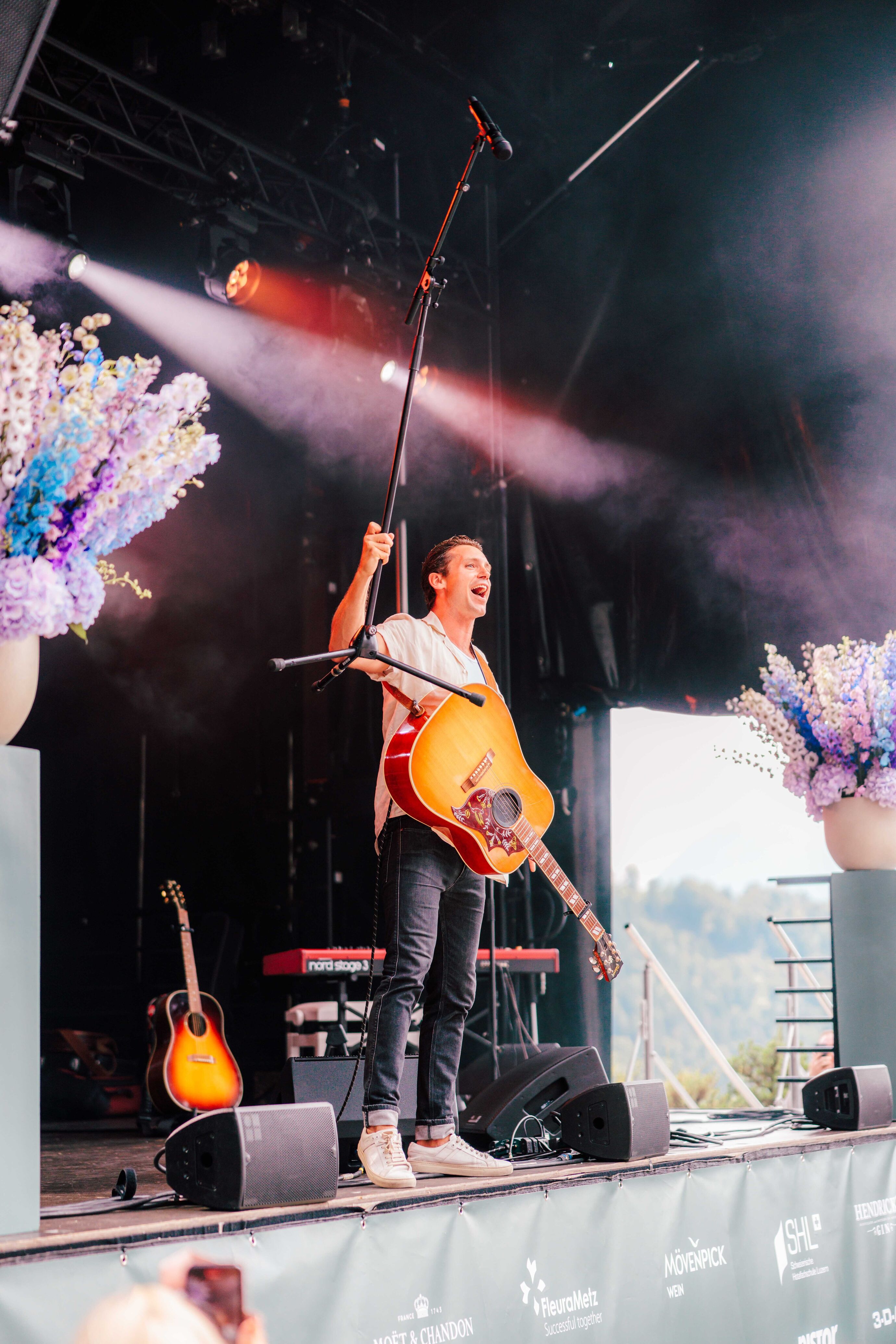 Sänger Bastian Baker hebt sein Mikrofon beim Auftritt am Bürgenstock Jubiläum 150 Jahre