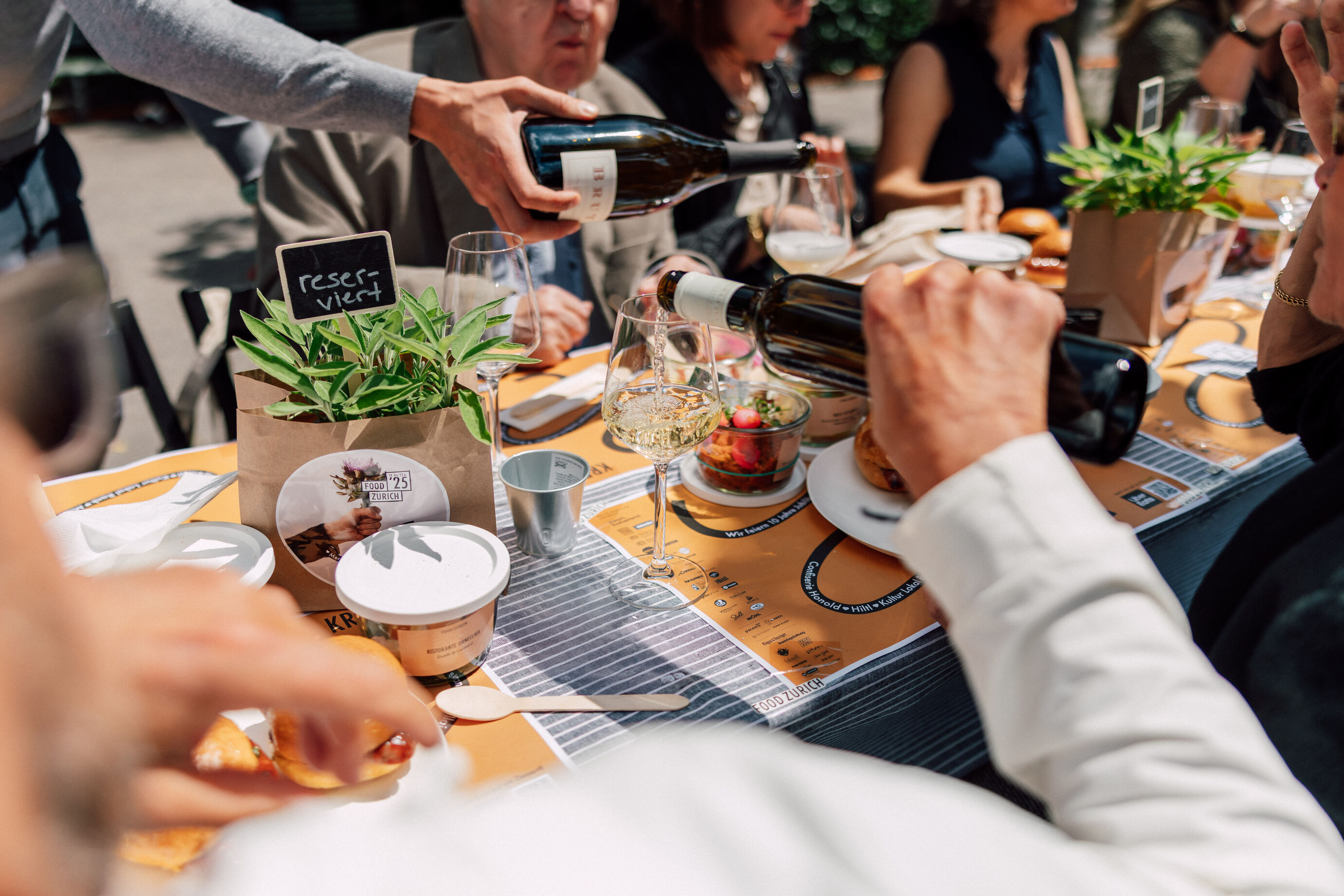 Weinflaschen werden an einer langen Tafel beim Food Festival Zürich eingeschenkt