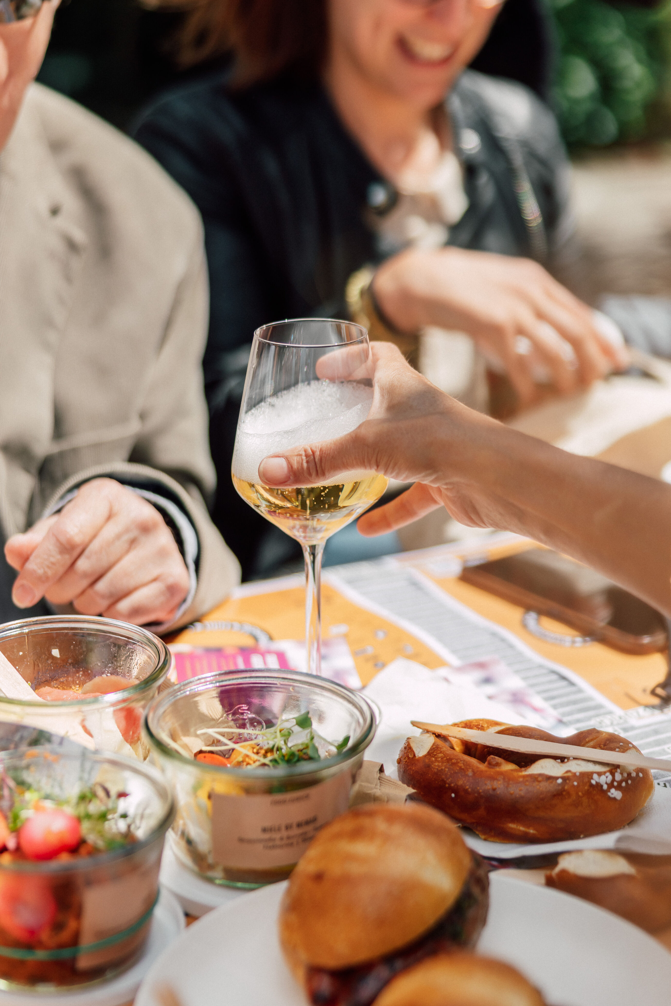 Nahaufnahme von Händen beim Anstossen mit Weisswein