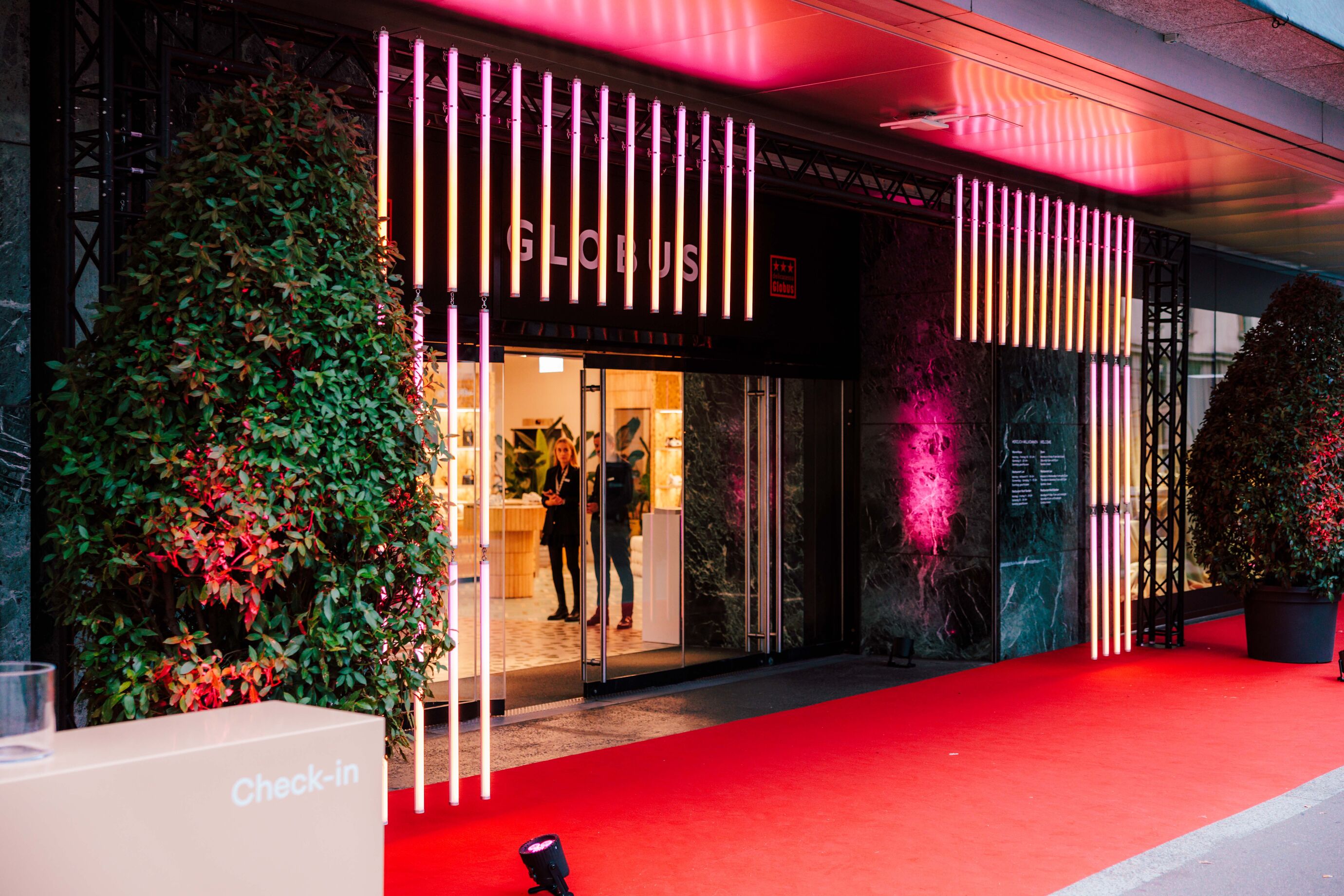 Der Eingang von Globus mit rotem Teppich und festlicher Beleuchtung.
