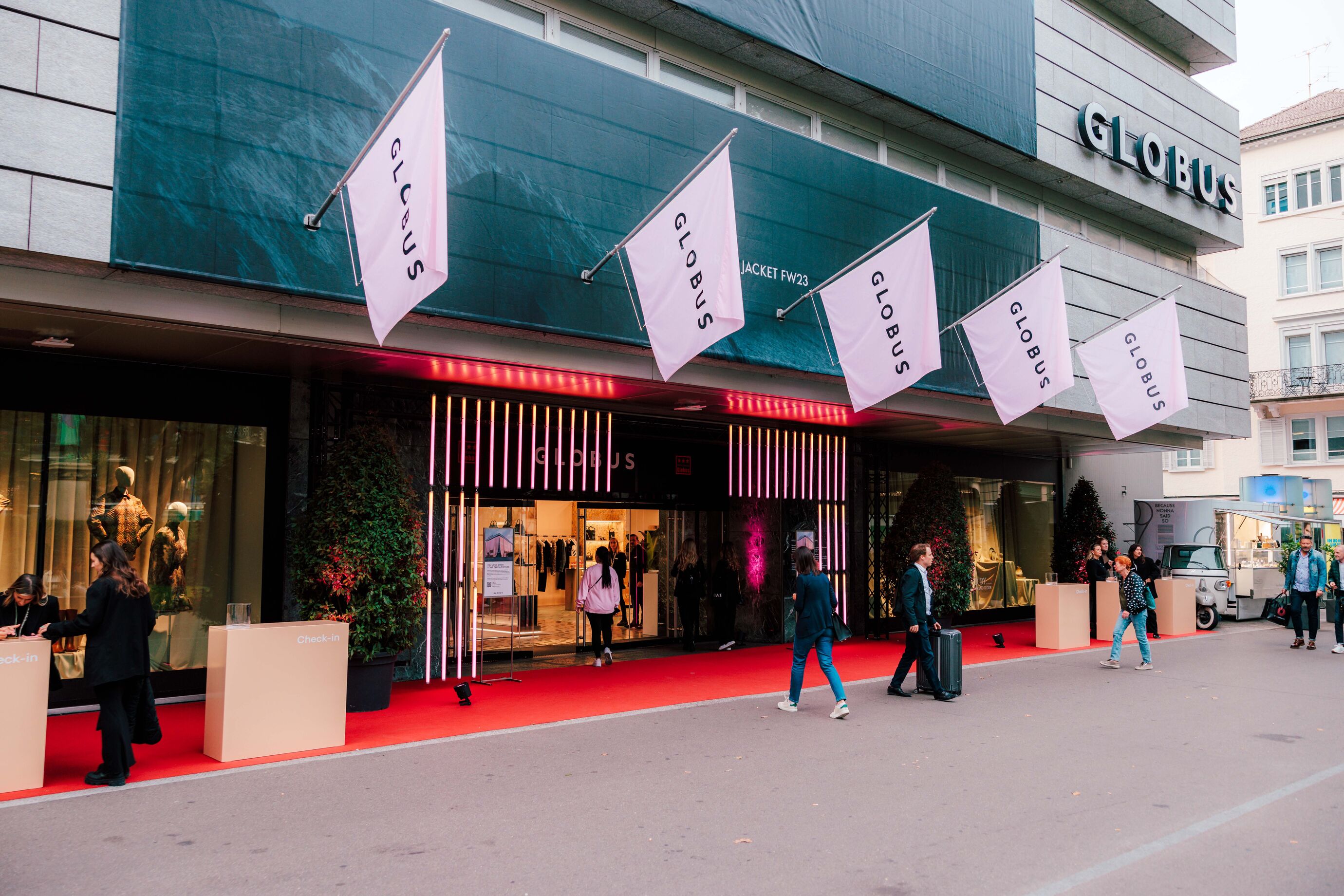 Eingang des Globus Zürich mit roten Teppich und Fahnen beim Womenswear Opening
