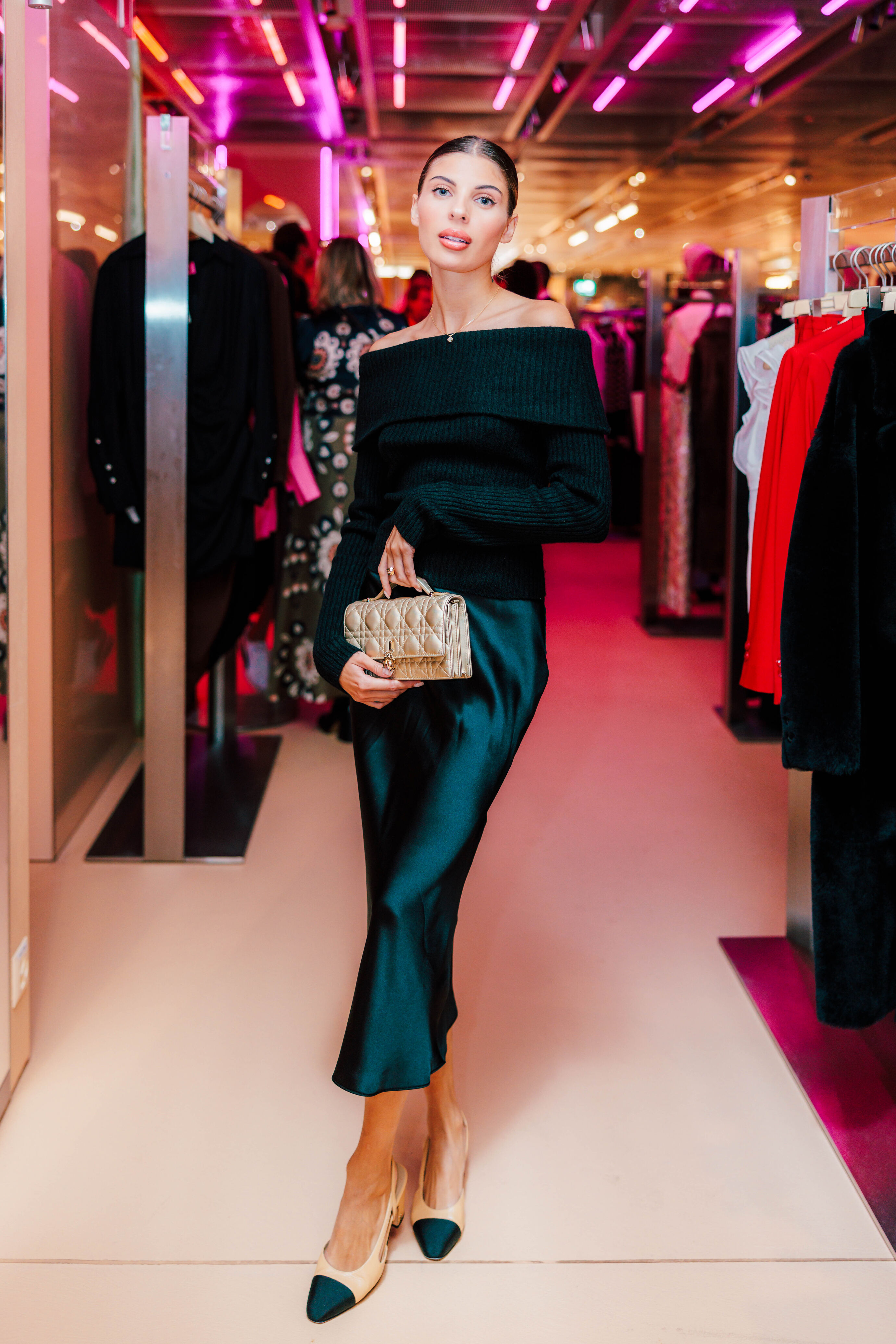 Frau in schwarzem Kleid mit goldener Tasche beim Opening