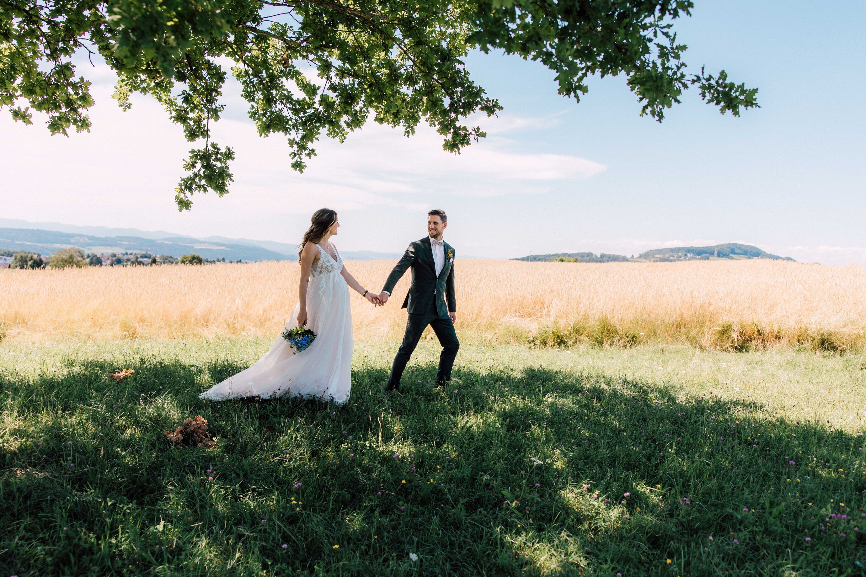 Hochzeitsfotografie Zürich – Brautpaar Hand in Hand auf Wiese