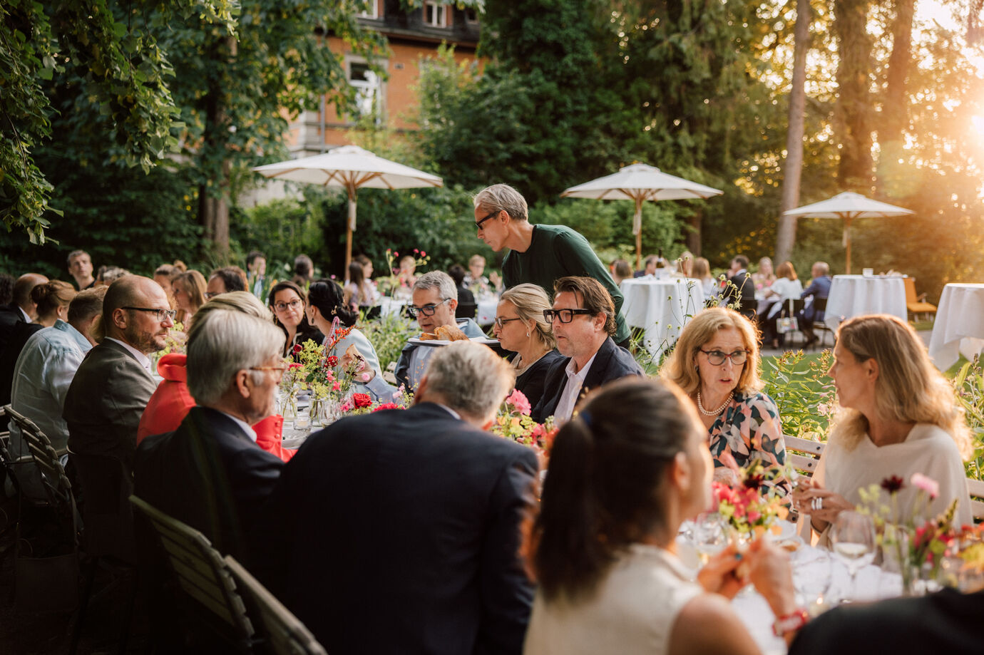 Eventfotograf Zürich Sommerfest mit langer Tafel und Gästen unter Laternen