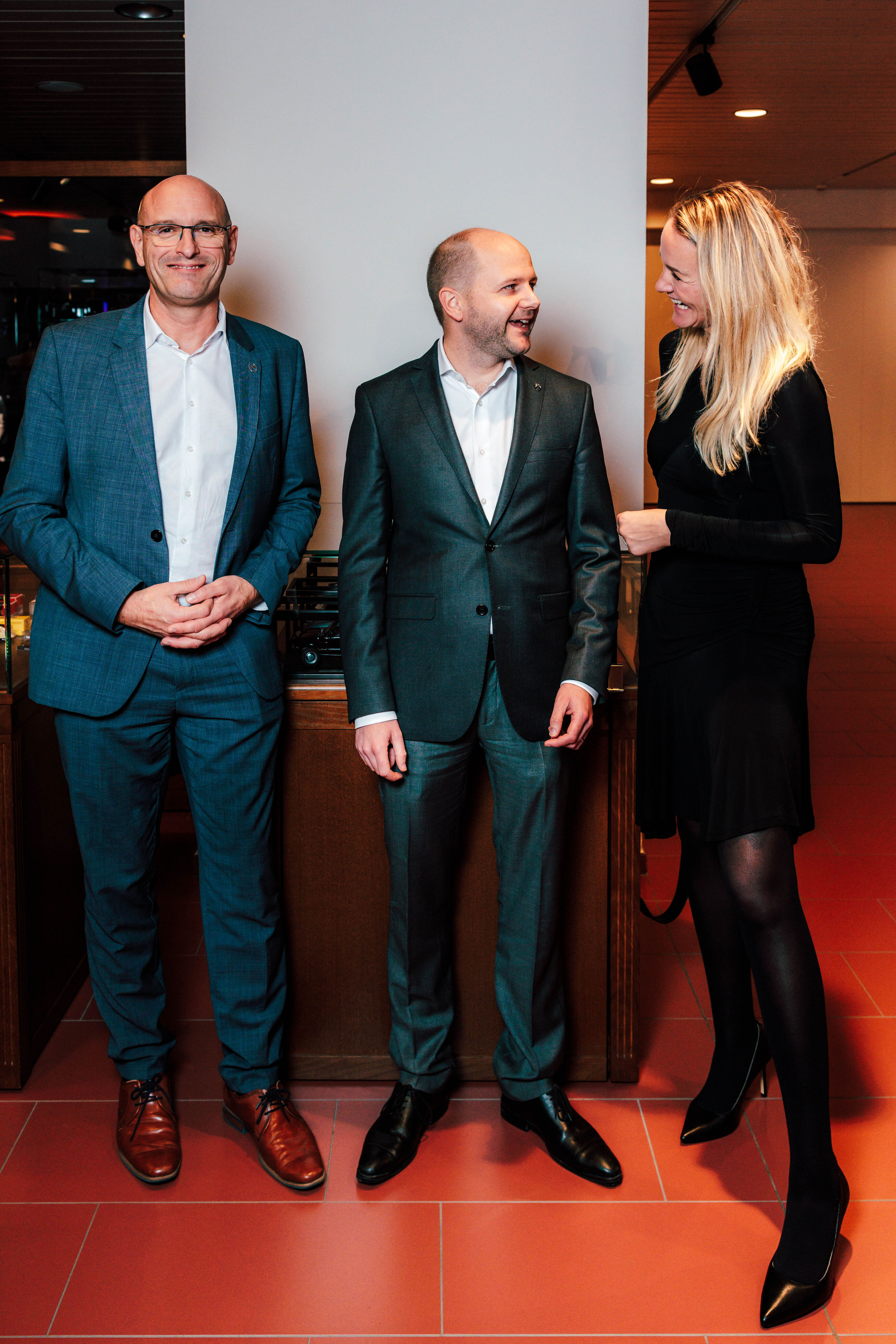 Zwei Männer im Anzug und eine Frau im Gespräch beim Event