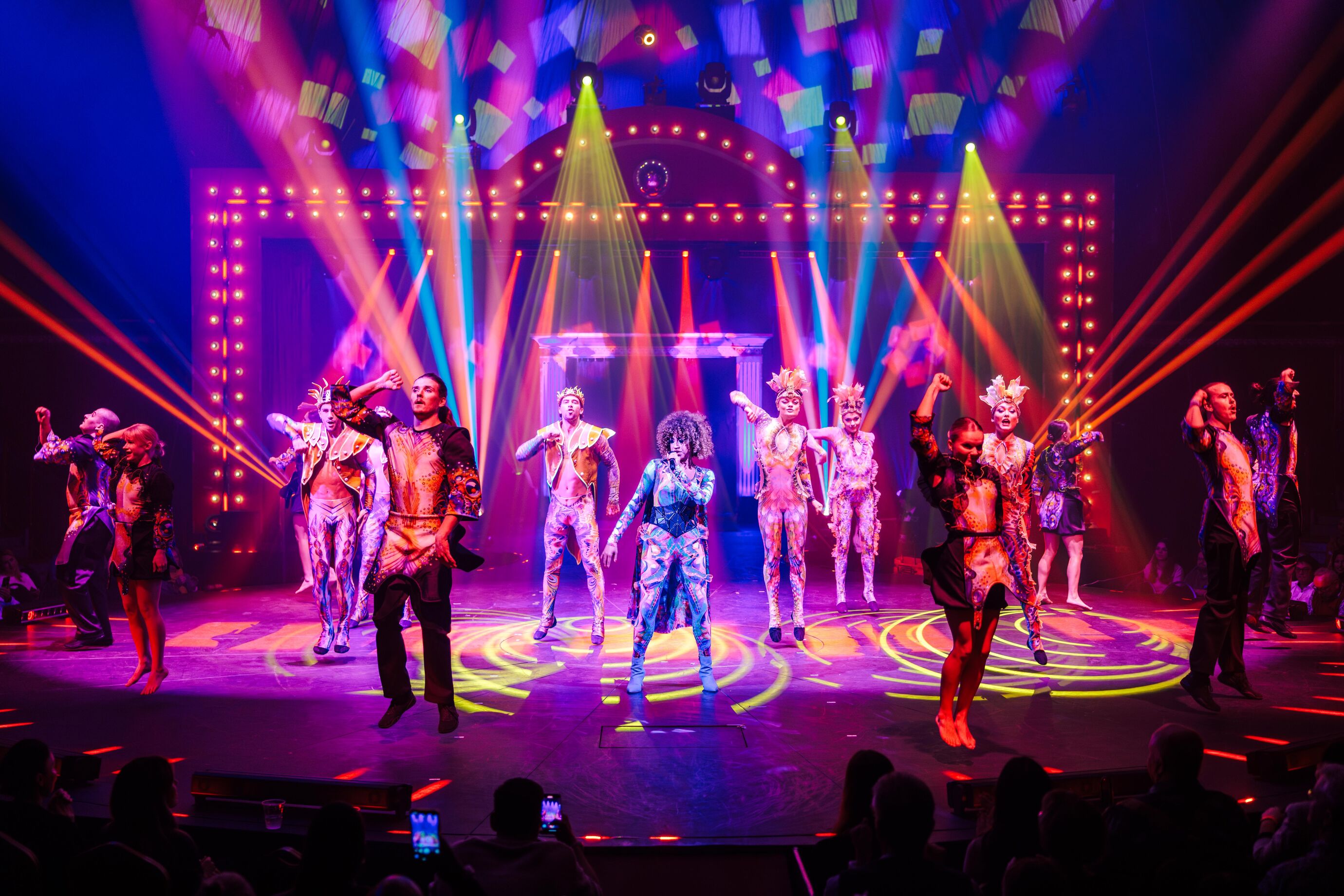 Akrobaten in bunten Kostümen performen unter Lichtstrahlen