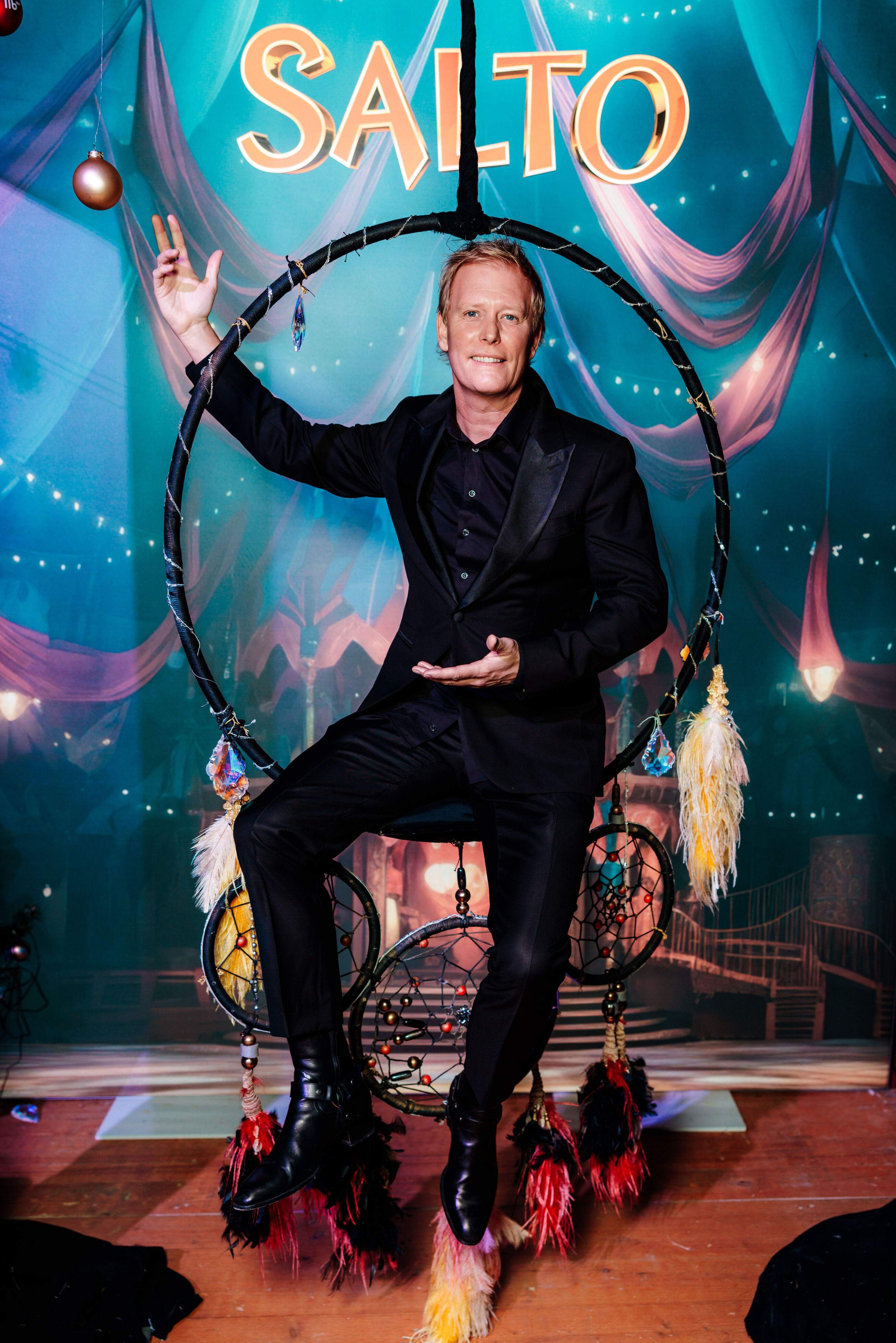 Artist sitzt in einem dekorativen Reifen auf der Bühne